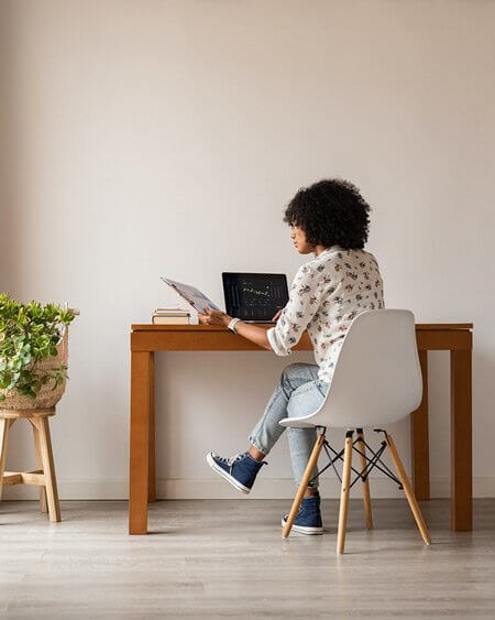 Image of female sitting at a desk reviewing a clipboard with a financial document attached to it.